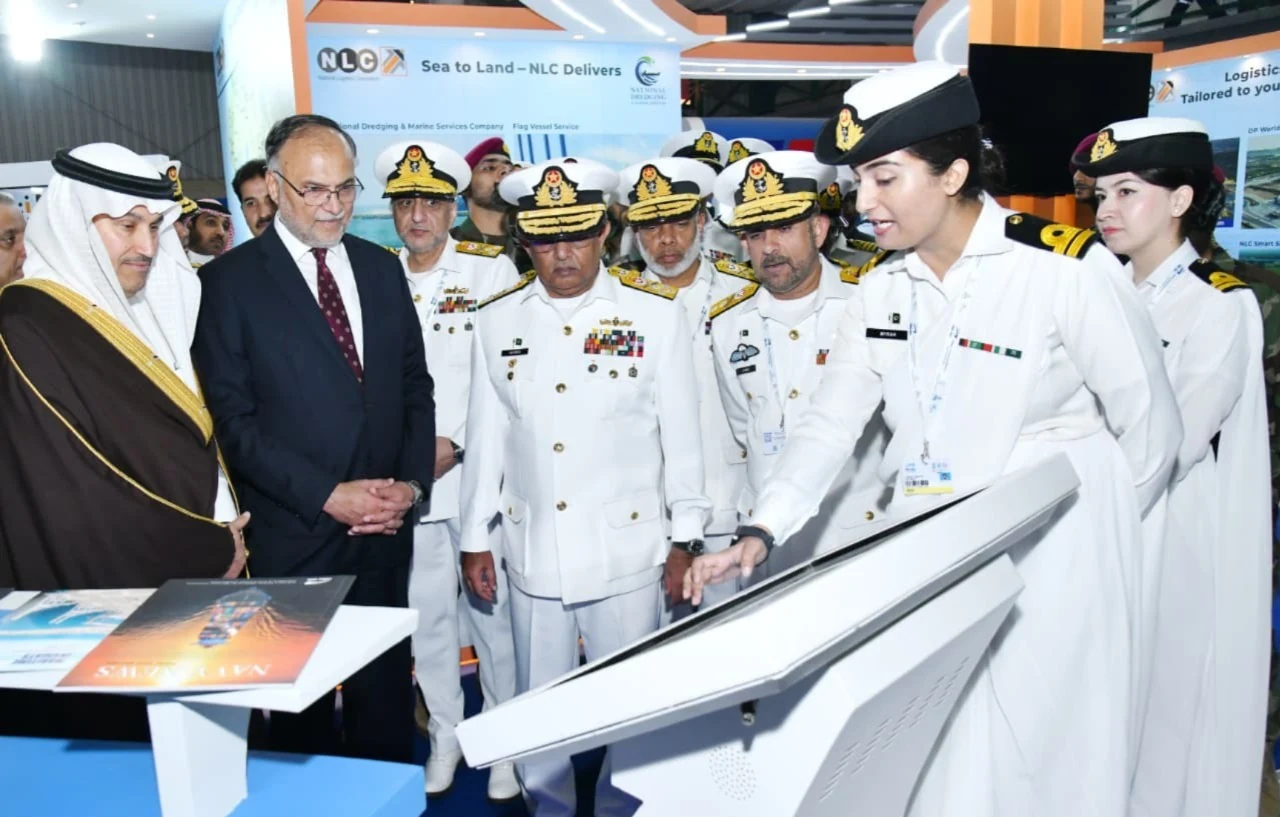Naval officers and exhibition delegates viewing a model ship.