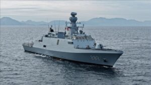 Gray military destroyer with hull number 282 cruising the calm sea with distant mountains on the horizon.