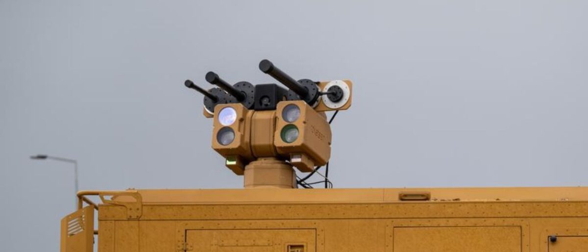 Yellow utility vehicle with a multi-lens traffic signal array on top, against a gray sky.