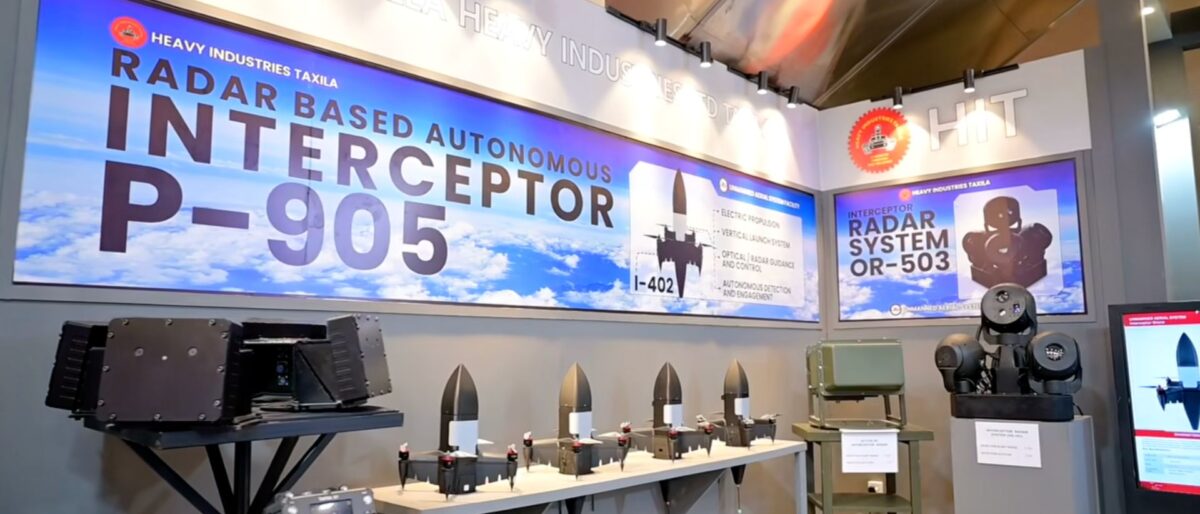 Exhibition booth displaying a large banner for radar-based autonomous interceptor P-905 with models and equipment on display.