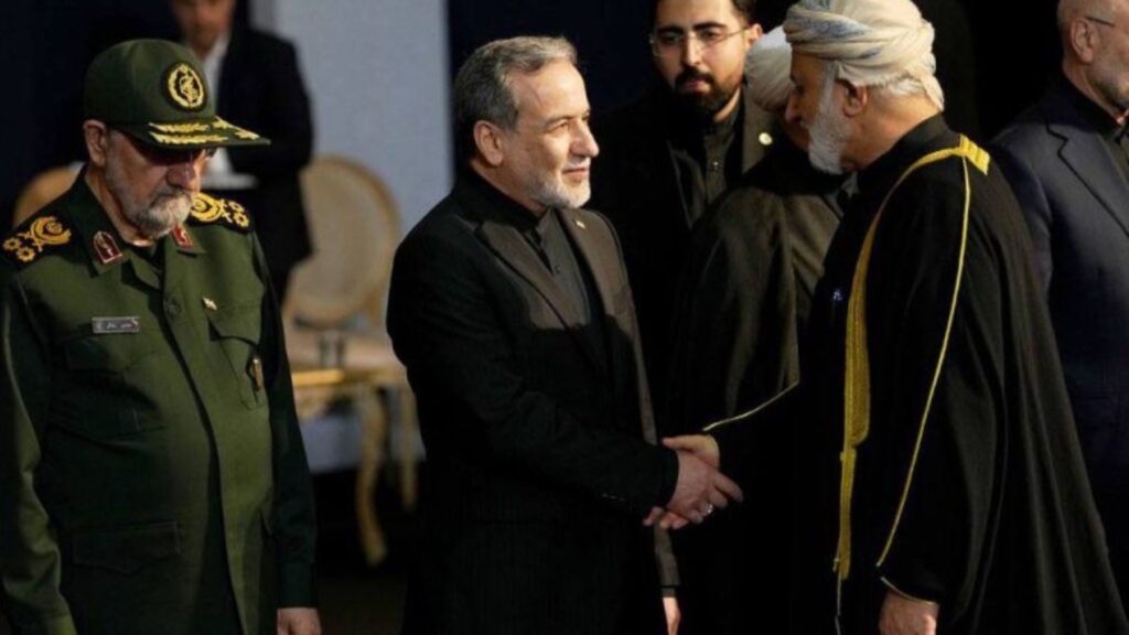 Three men in formal attire greet each other: a high-ranking military officer in a green uniform on the left, a man in a black suit in the center, and a cleric with a white turban on the right.