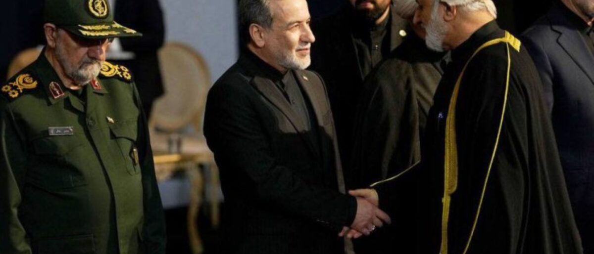 Three men in formal attire greet each other: a high-ranking military officer in a green uniform on the left, a man in a black suit in the center, and a cleric with a white turban on the right.