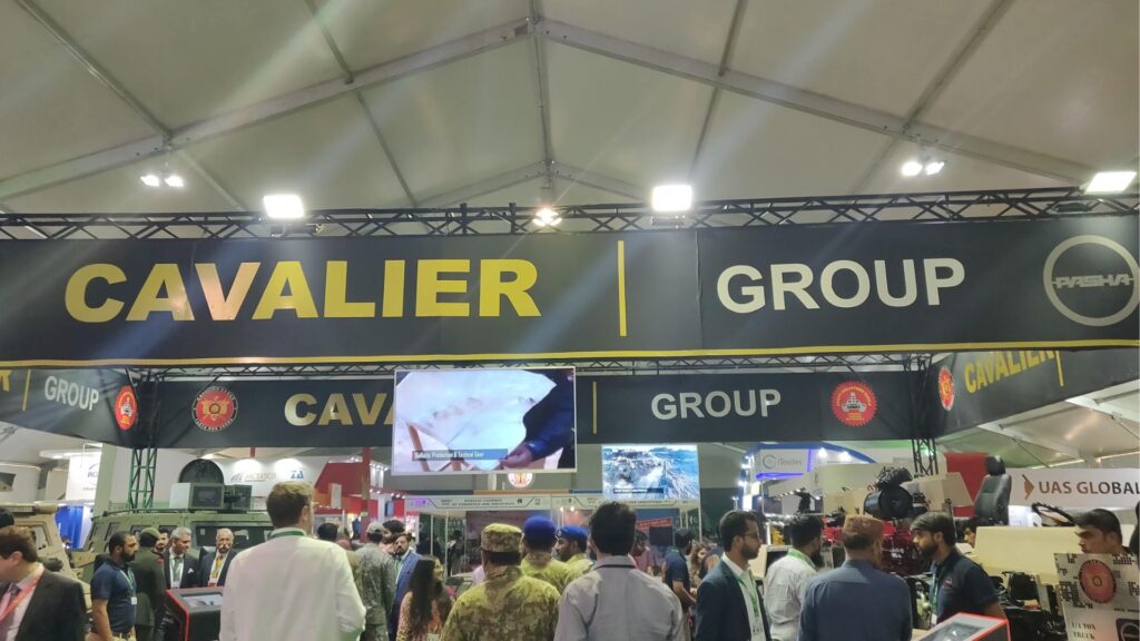 Large overhead sign reads 'CAVALIER GROUP' in yellow letters on a dark backdrop at an indoor exhibition, with a crowd of attendees below.