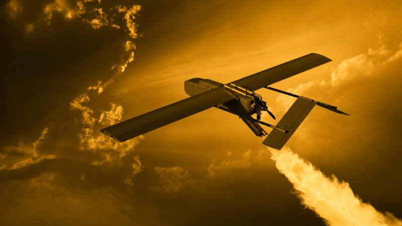 Unmanned aerial vehicle with long wings flying through a golden sunset sky.