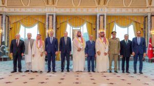 Group of dignitaries in formal and traditional dress posing for a ceremony in a grand, gilded hall with yellow drapes; Pakistan and Turkey flags visible on each side.