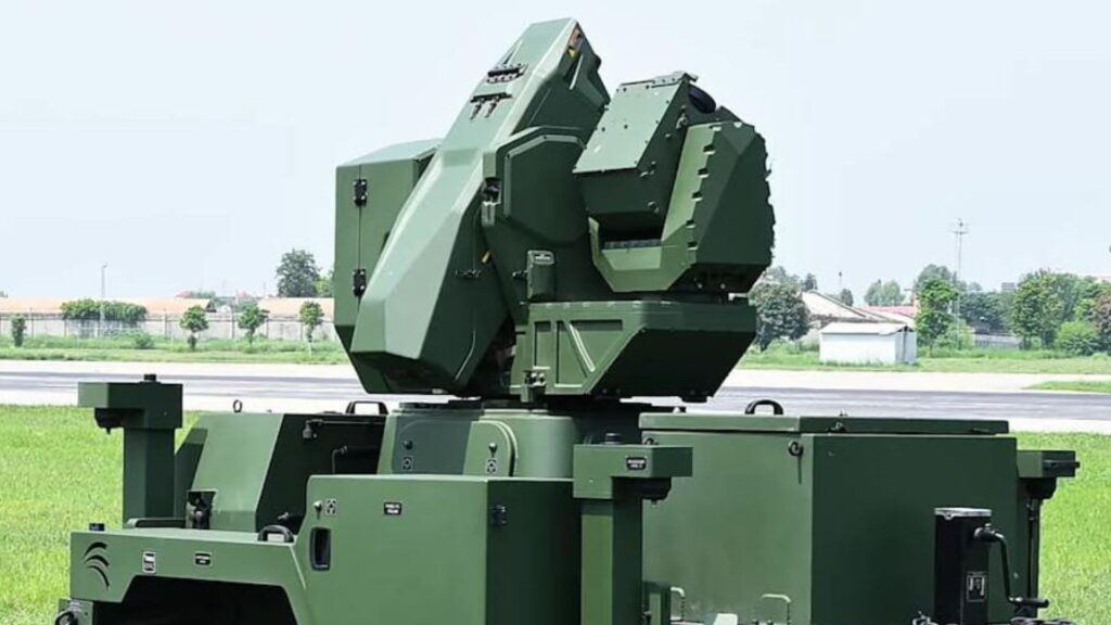 Green military mobile launcher with an elevated array mounted on a tracked chassis, outdoors on grass server side.