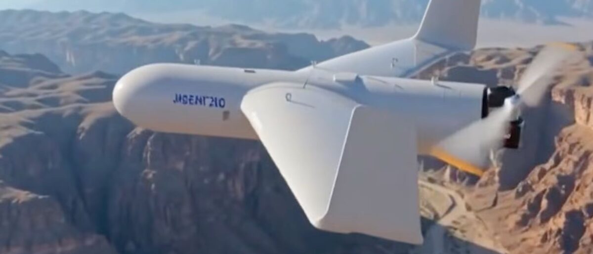 White futuristic unmanned aircraft with a V-tail gliding over a deep canyon landscape.