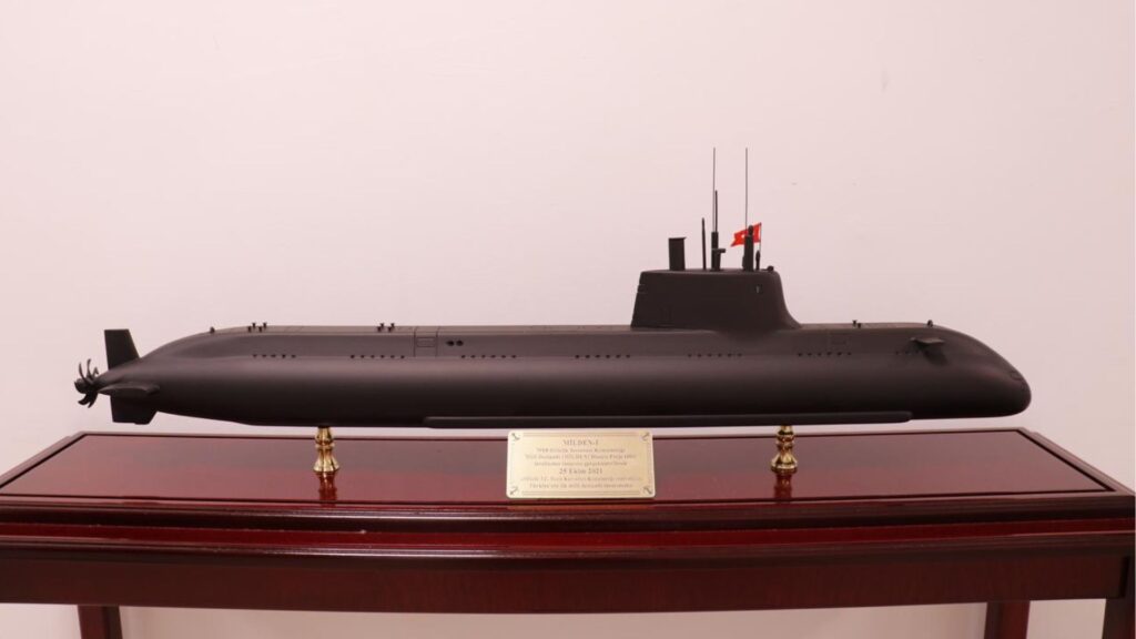 Black submarine model on a polished wooden display case with a plaque in front.