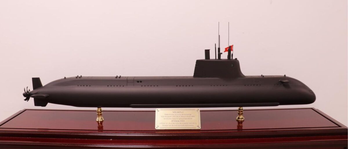 Black submarine model on a polished wooden display case with a plaque in front.