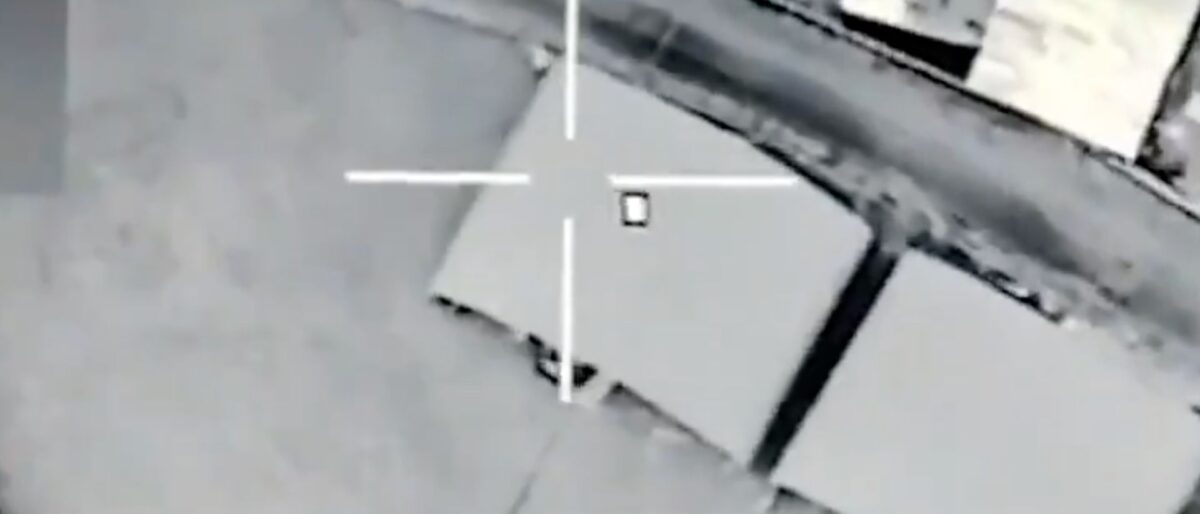 Drone-style targeting view: a gray rooftop with a white crosshair centered on a gray crate.