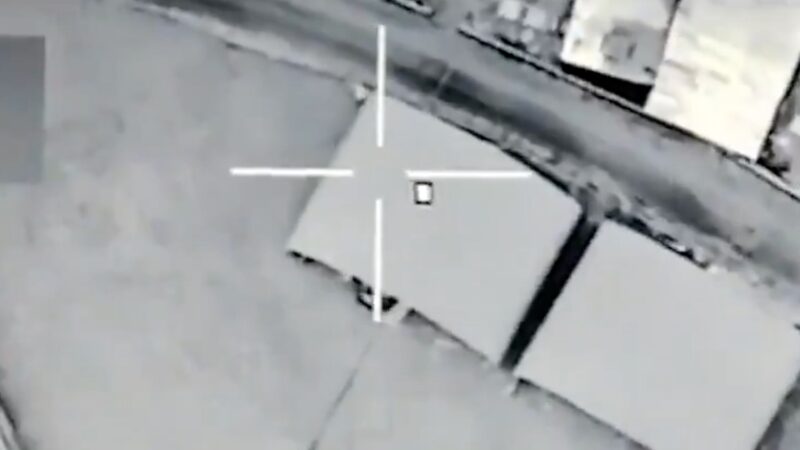 Drone-style targeting view: a gray rooftop with a white crosshair centered on a gray crate.