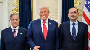 Three men in dark suits posing for a formal photo in a room with blue curtains and a visible U.S. flag, smiling at the camera.