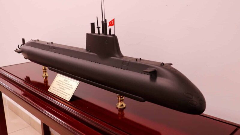 Scale model submarine with a Turkish flag on top, mounted on a polished wooden display stand with a plaque.