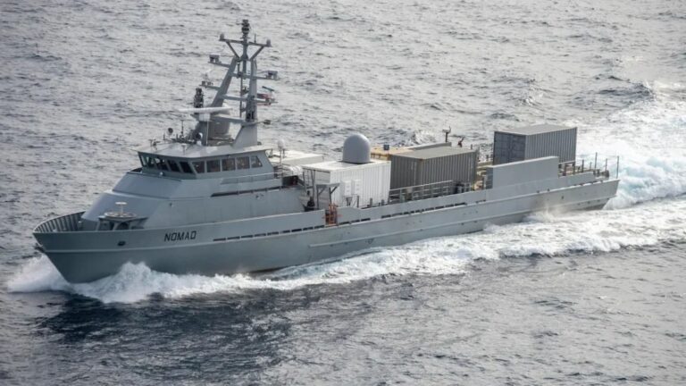 Containerized Munitions - Quwa Gray research/support vessel named Nomad cuts through waves with stacked cargo containers on its deck.