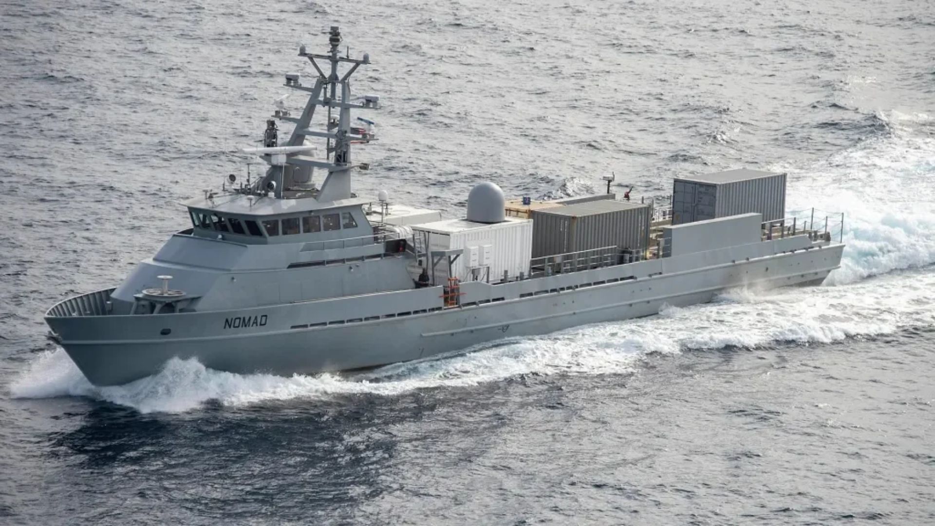 Containerized Munitions - Quwa Gray research/support vessel named Nomad cuts through waves with stacked cargo containers on its deck.
