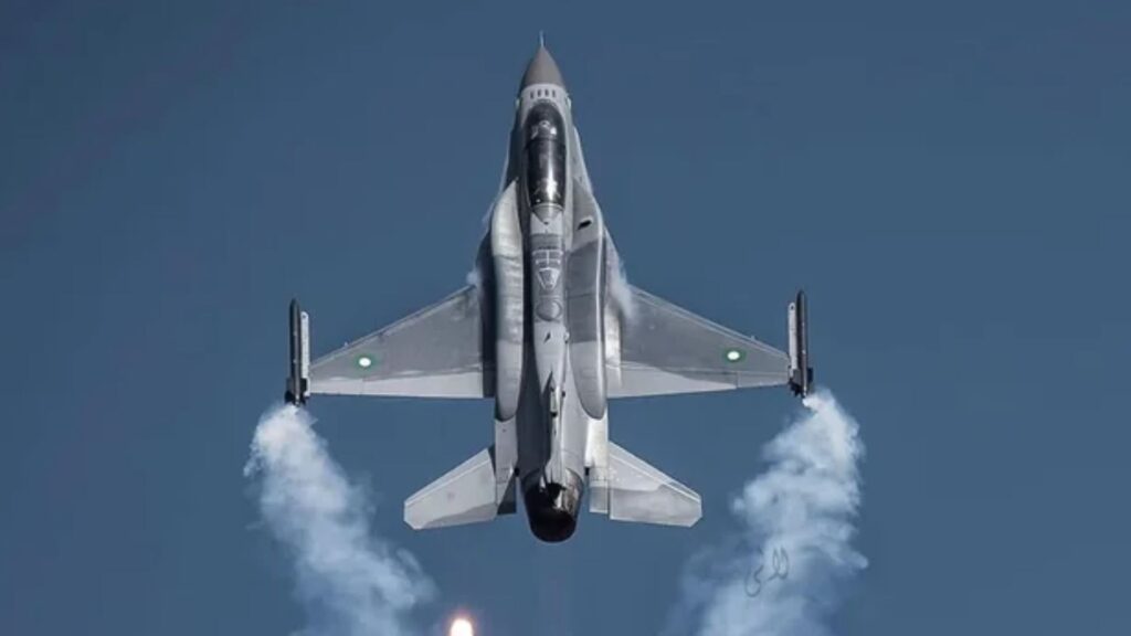 Top-down view of a gray fighter jet in a high-speed vertical climb, exhaust glowing and white smoke plumes trailing behind it