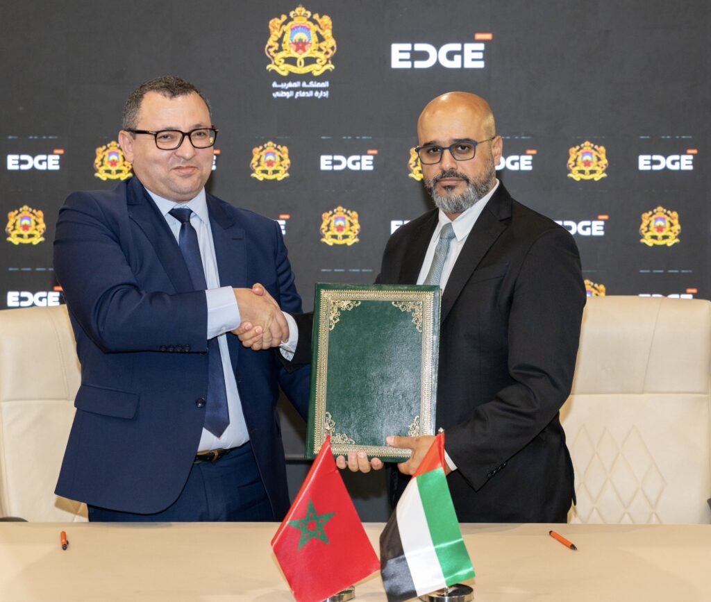 Representatives shake hands and hold a document folder at the EDGE–Morocco agreement signing