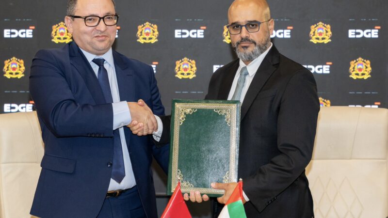 Representatives shake hands and hold a document folder at the EDGE–Morocco agreement signing