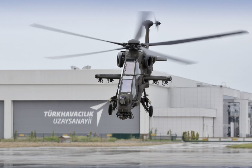 TUSAŞ T129 ATAK attack helicopter hovering in front of a Turkish Aerospace hangar
